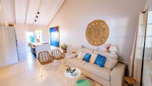 A modern living room with a sofa, chairs, a coffee table, and a large woven wall hanging. - NEW 2BR Escape | Plunge Pool & BBQ | Near Beaches (Noord)