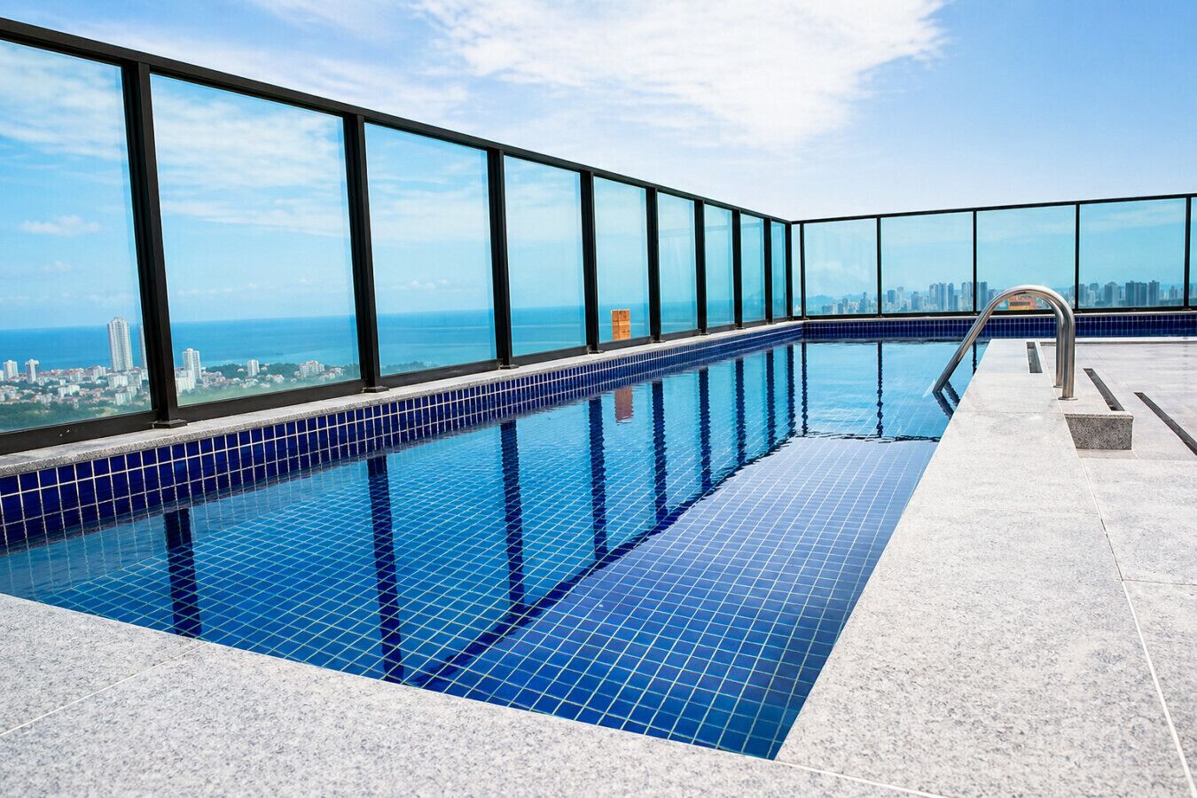 Piscina infinita no terraço com azulejos azuis e um deck revestido, com vista para a cidade.