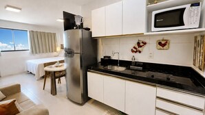 Une cuisine moderne équipée d’un réfrigérateur, d’un four à micro-ondes et d’une cuisinière. Un coin repas avec une table et des chaises est également disponible.