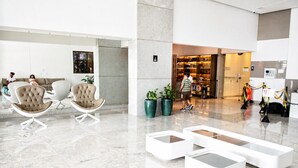 Un hall d’entrée moderne doté d’espaces de détente, d’un comptoir d’accueil et offrant une vue sur la ville la nuit.