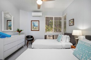 Une chambre d’hôtel avec un lit, un bureau, une chaise, une fenêtre avec des volets et un ventilateur de plafond.