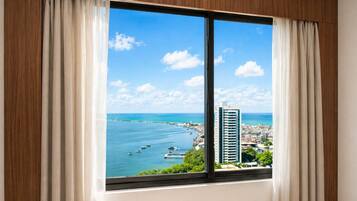 Janela com vista para um horizonte costeiro, incluindo um prédio alto e um porto de iates.