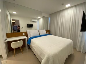 Une chambre d’hôtel comprenant un lit, un bureau, une chaise, une télévision et un miroir.