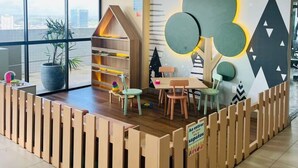 A children's play area with a wooden playhouse, tables, chairs, and a large wall mural. - Beach Class Hotels & Residence -Boa Viagem- Flat A (Boa Viagem)