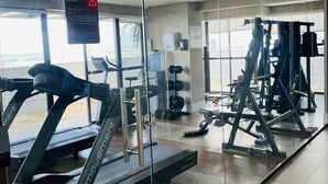 A fitness center with treadmills, weight machines, and a mirrored wall. - Beach Class Hotels & Residence -Boa Viagem- Flat A (Boa Viagem)