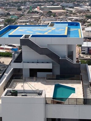 Un bâtiment moderne doté d’une piscine sur le toit, d’un escalier et offrant une vue sur le paysage urbain environnant.