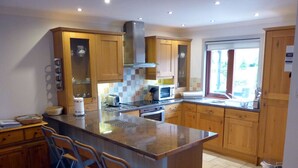 A modern kitchen with wooden cabinets, a central island with bar stools, a microwave, and a gas stove.