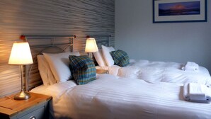 A hotel room with a bed, two bedside lamps, a nightstand, and a framed picture on the wall.