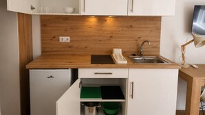 A compact kitchen with white cabinets, a wooden countertop, a built-in sink, and a small refrigerator. - Aparthotel Fuenlabrada Central (Fuenlabrada)