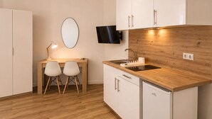 A modern kitchen with wooden countertops, a built-in dishwasher, and a flat-screen TV mounted above the sink. - Aparthotel Fuenlabrada Central (Fuenlabrada)