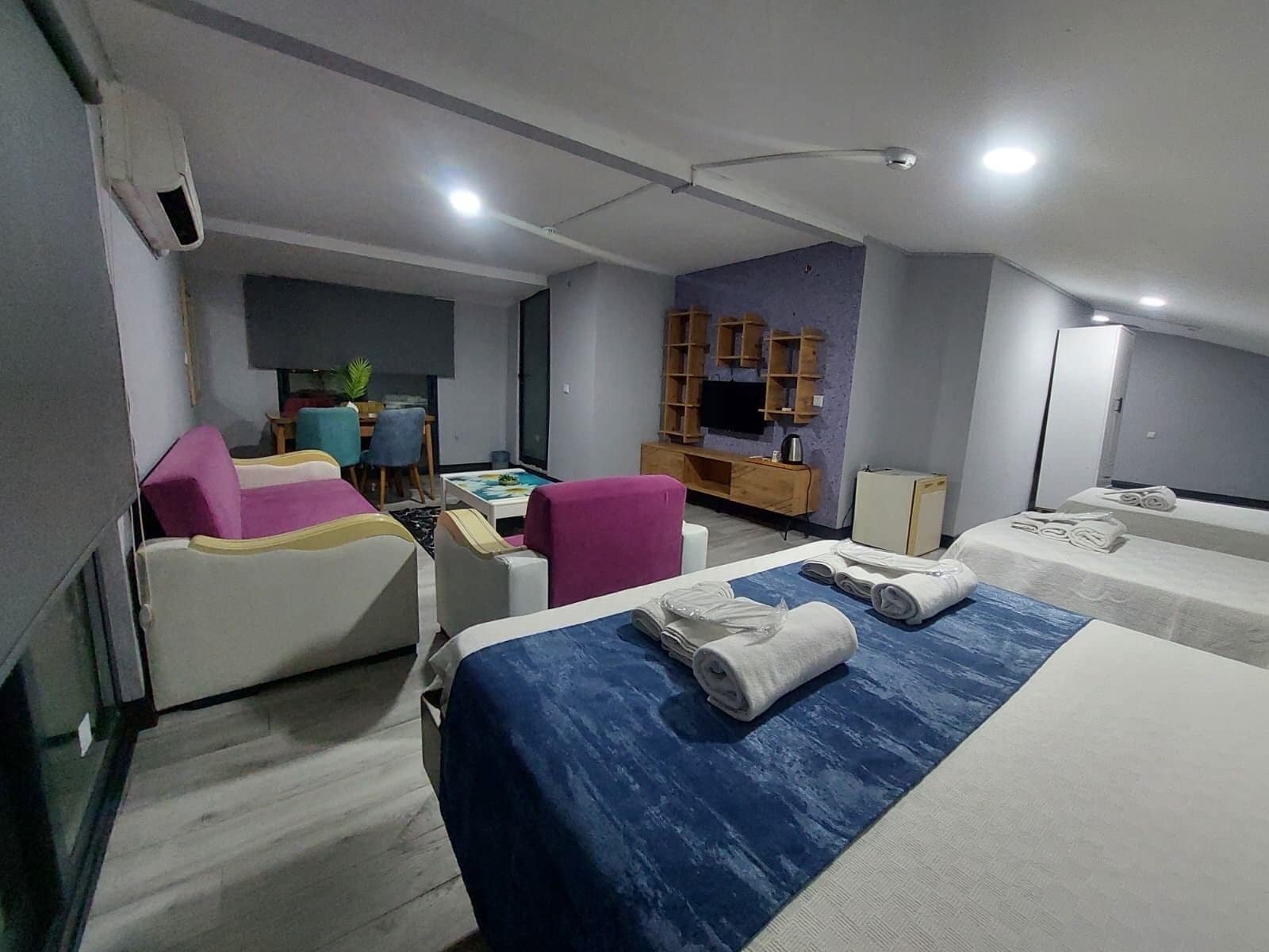 A hotel room with two beds, a desk, a chair, a television, and a small kitchenette.