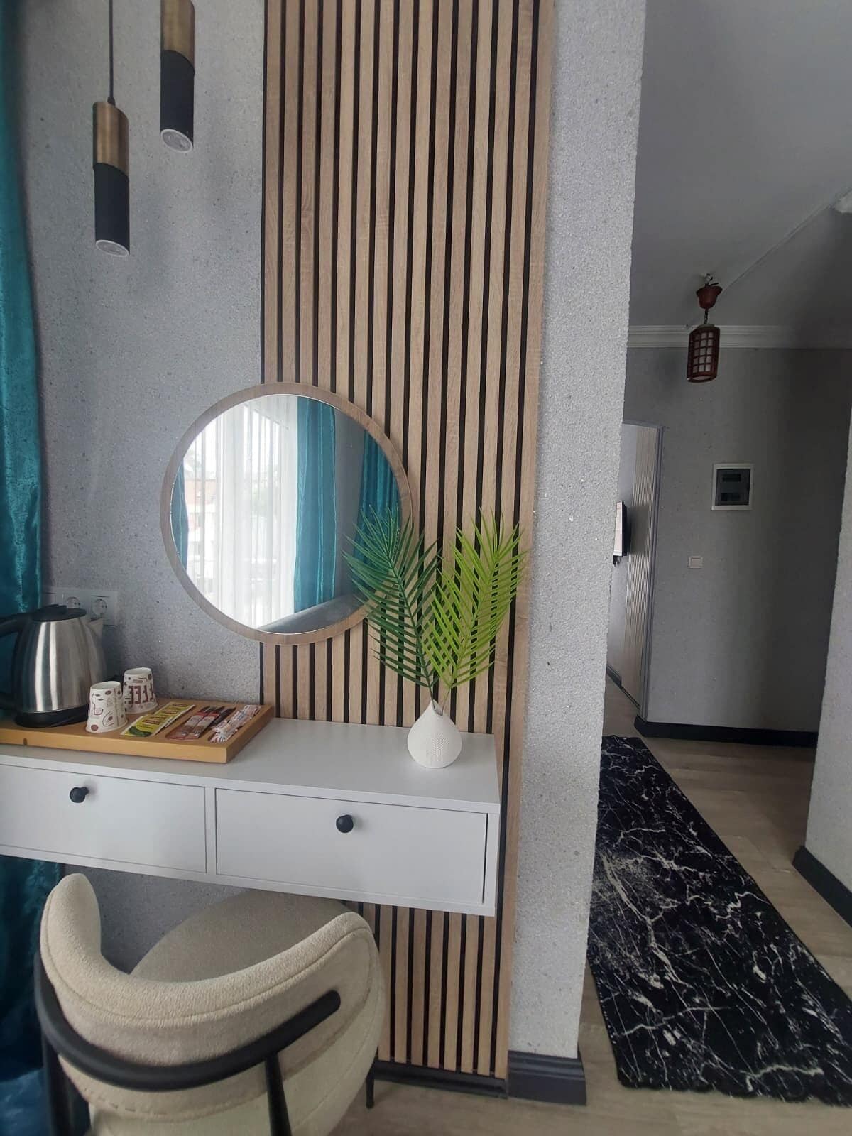 A modern room with a desk, a round mirror, a potted plant, and a black and white marble floor.
