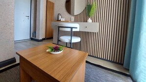 A modern room with a wooden desk, a white chair, a round mirror, a small plant, and a vertical wooden panel. - dolunaydın otel (Manavgat)