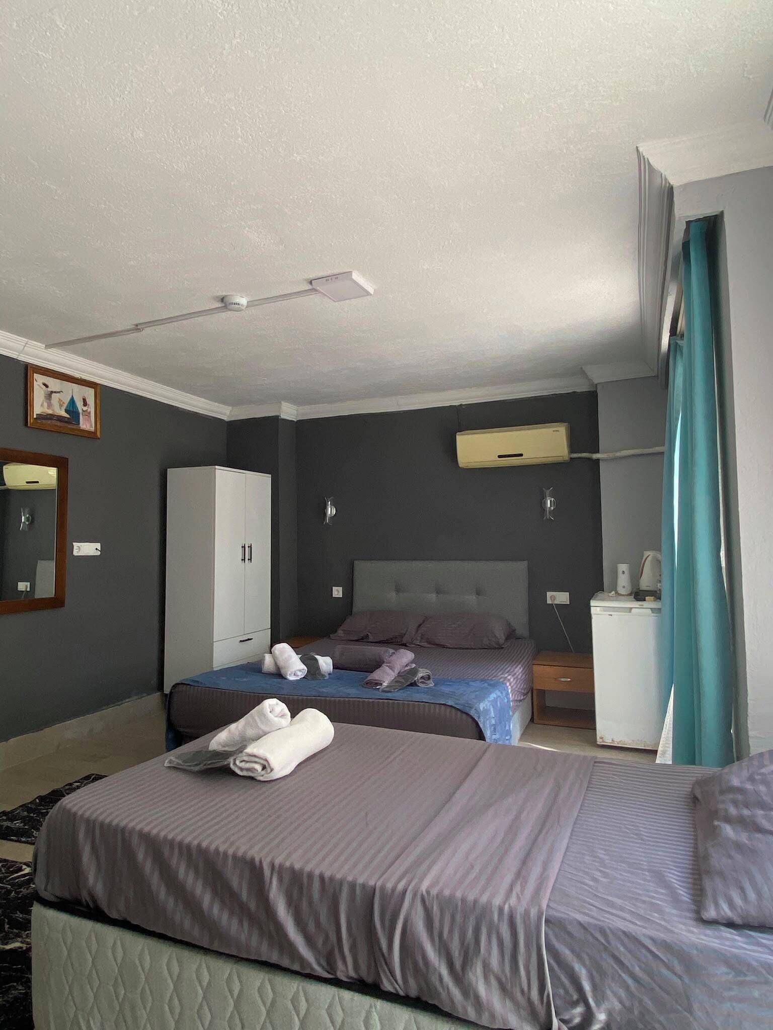 A hotel room with a bed, a wardrobe, a bedside table, a lamp, and a ceiling fan.