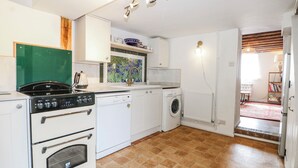 A compact kitchen with a stove, dishwasher, and washing machine. - Quince Cottage (Lewes)