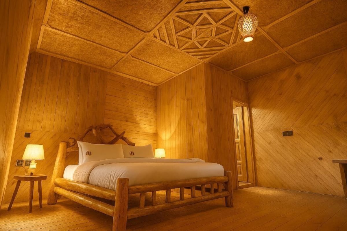 Una habitación de madera con una cama, dos lámparas de noche y un diseño geométrico en el techo.