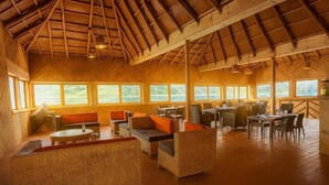 A spacious indoor area with wicker furniture, large windows, and a wooden ceiling.