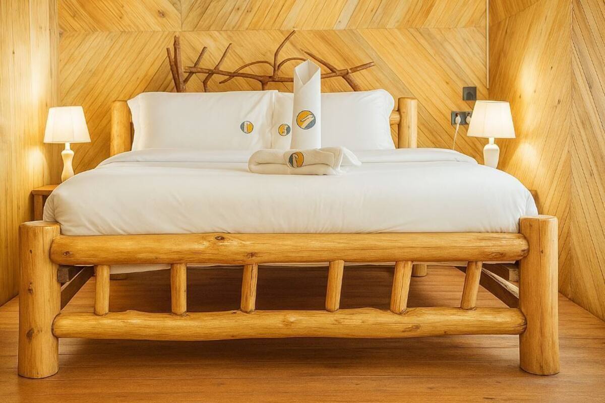 Una cama de madera con cabecera, dos lámparas de noche y una toalla sobre la cama.