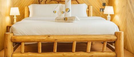 A wooden bed with a headboard, two bedside lamps, and a towel on the bed.