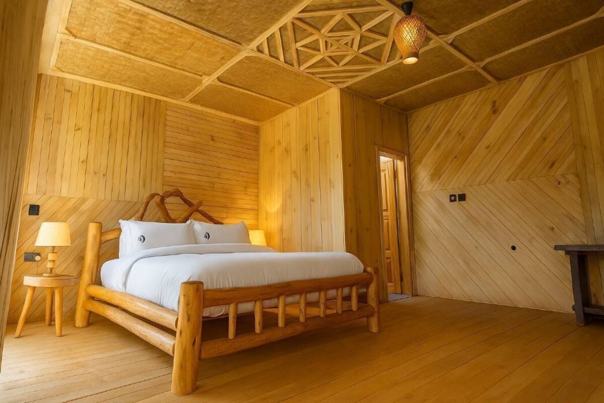 Una habitación de madera con una cama, una mesita de noche y una lámpara.