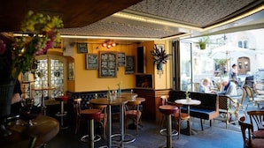 An interior with tables and chairs, a bench, and a wall with various signs. - KBCityRooms (Lucerne)
