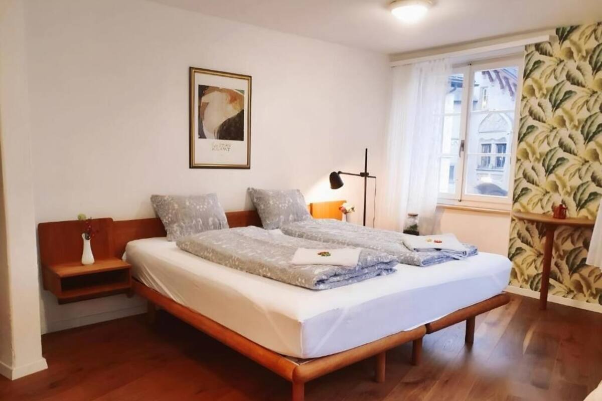 A neatly made bed with pillows, a bedside table with a lamp, and a framed picture on the wall.