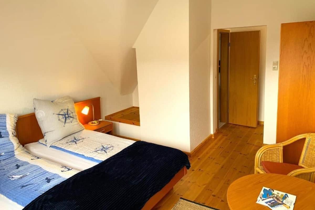 A bedroom with a bed, bedside table, lamp, and a chair.