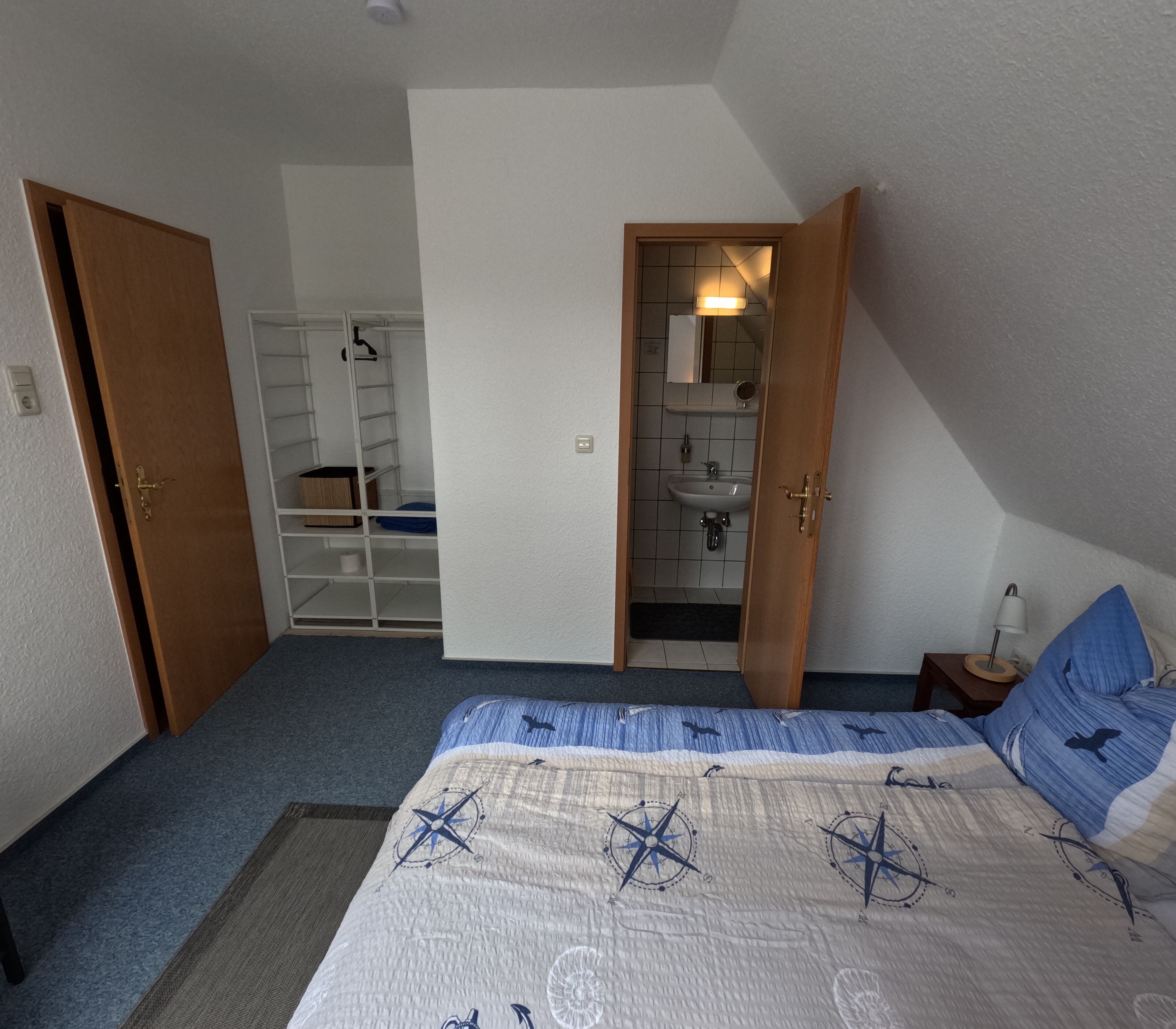 A bedroom with a bed, a wardrobe, and a bathroom visible through an open door.