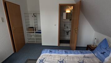 A bedroom with a bed, a wardrobe, and a bathroom visible through an open door.