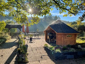 A wooden gazebo, a barbecue area, and a brick patio with potted plants. - Kiek Inn (Hitzacker)