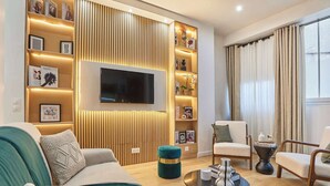 Una sala de estar moderna con un televisor de pantalla plana, un sofá, una mesa de centro y una silla.