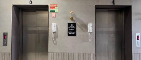 Two elevator doors labeled '5' and '4' with signs indicating 'FLOOR - 6 To 11' and 'RECEPTION 8th FLOOR'.