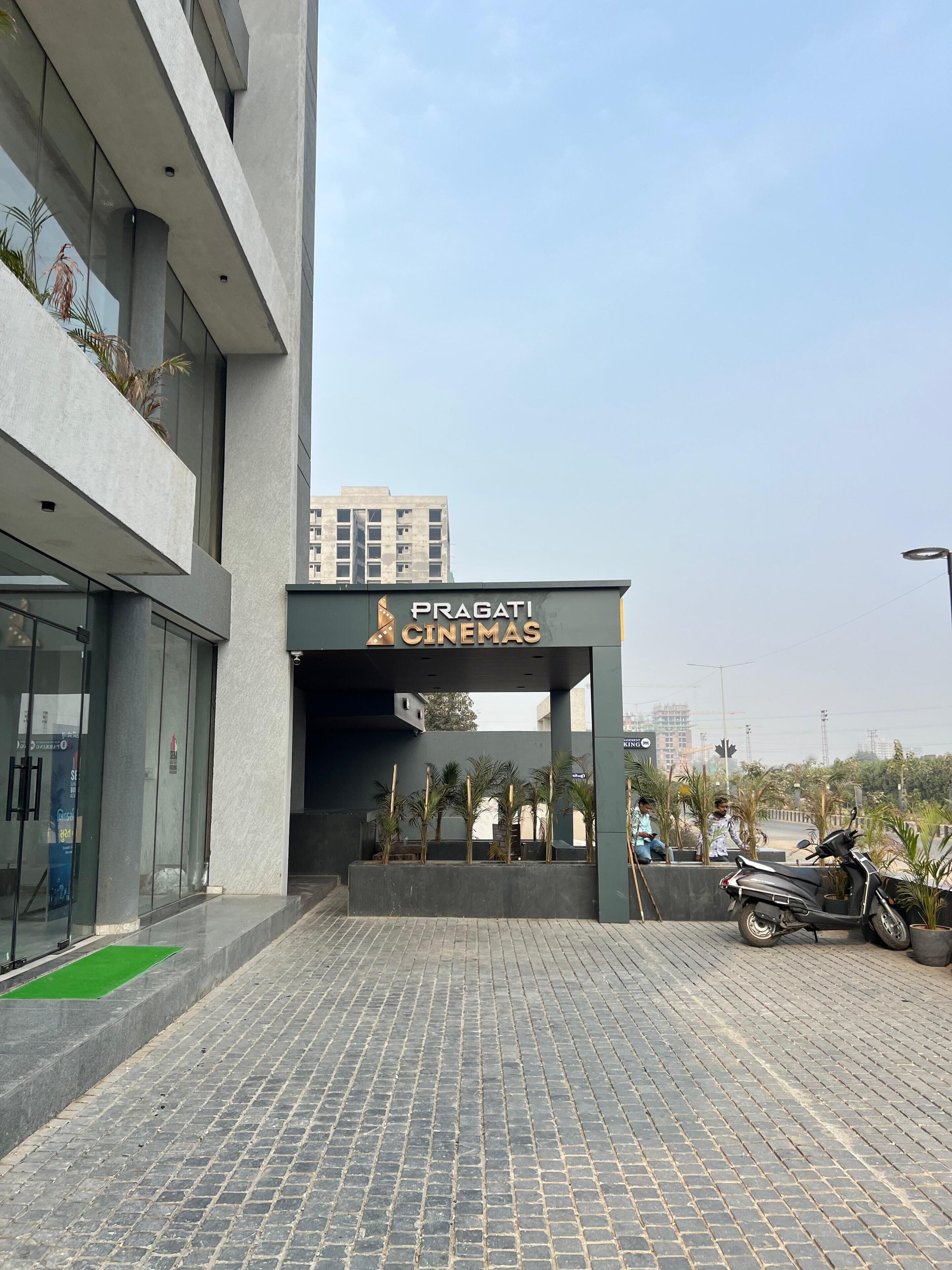 A modern building with a sign for 'Pragati Cinemas' at the entrance.