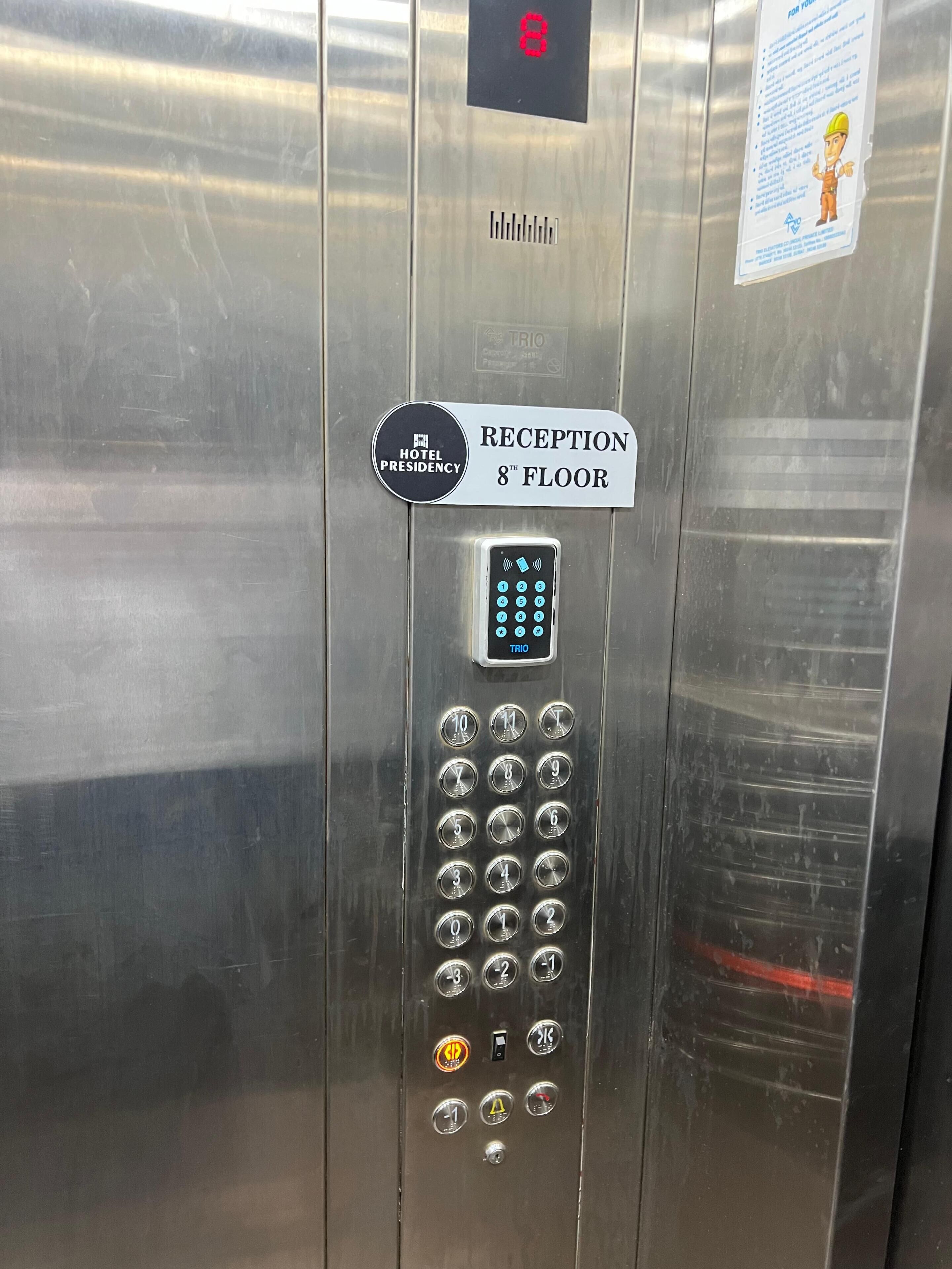 An elevator control panel with a digital display, a keypad, and a sign indicating the 8th floor reception.