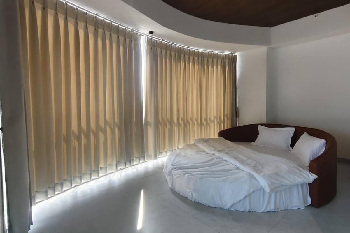 A bedroom with a bed, curtains, and a curved ceiling.