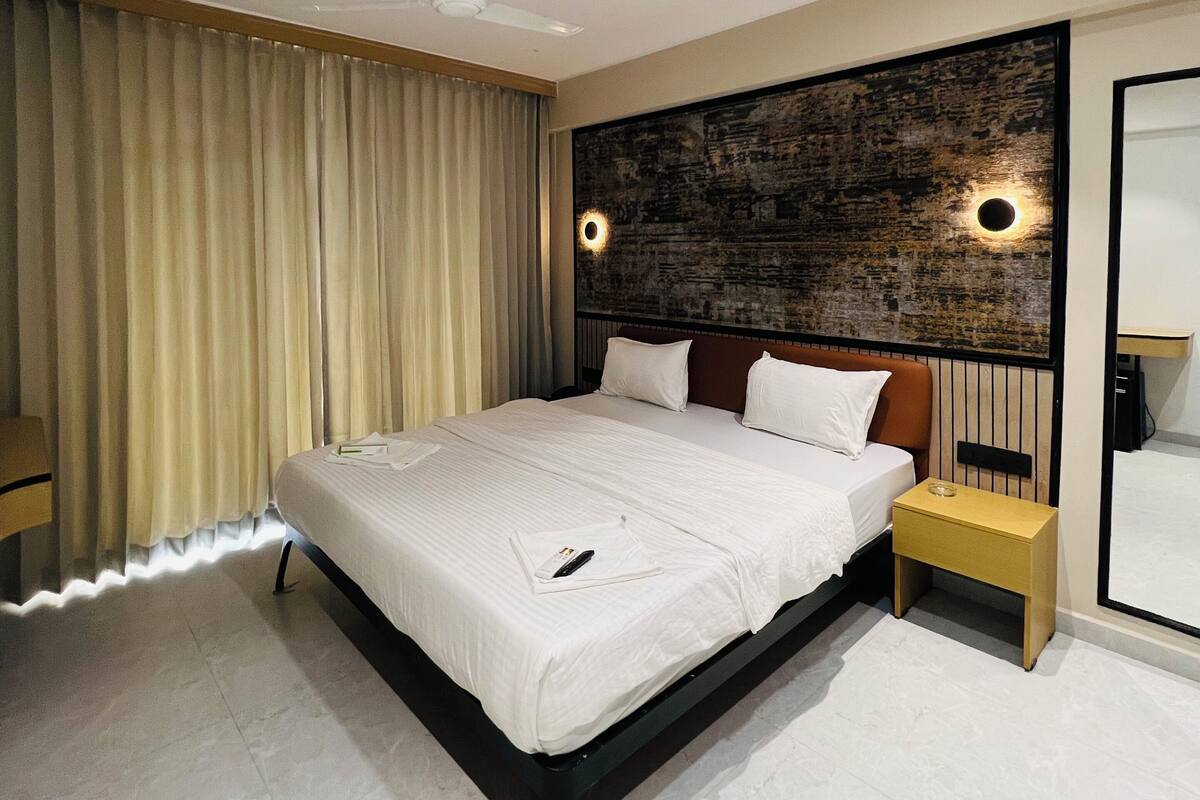 A modern hotel room with a large bed, a ceiling fan, a nightstand, and a wall-mounted TV.