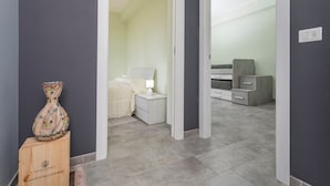 A hallway leading to a bedroom with a nightstand, lamp, and a decorative vase. - Villa Veronica – with Sea View (Mascali)