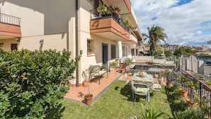A residential building with a balcony, potted plants, and outdoor furniture. - Villa Veronica – with Sea View (Mascali)