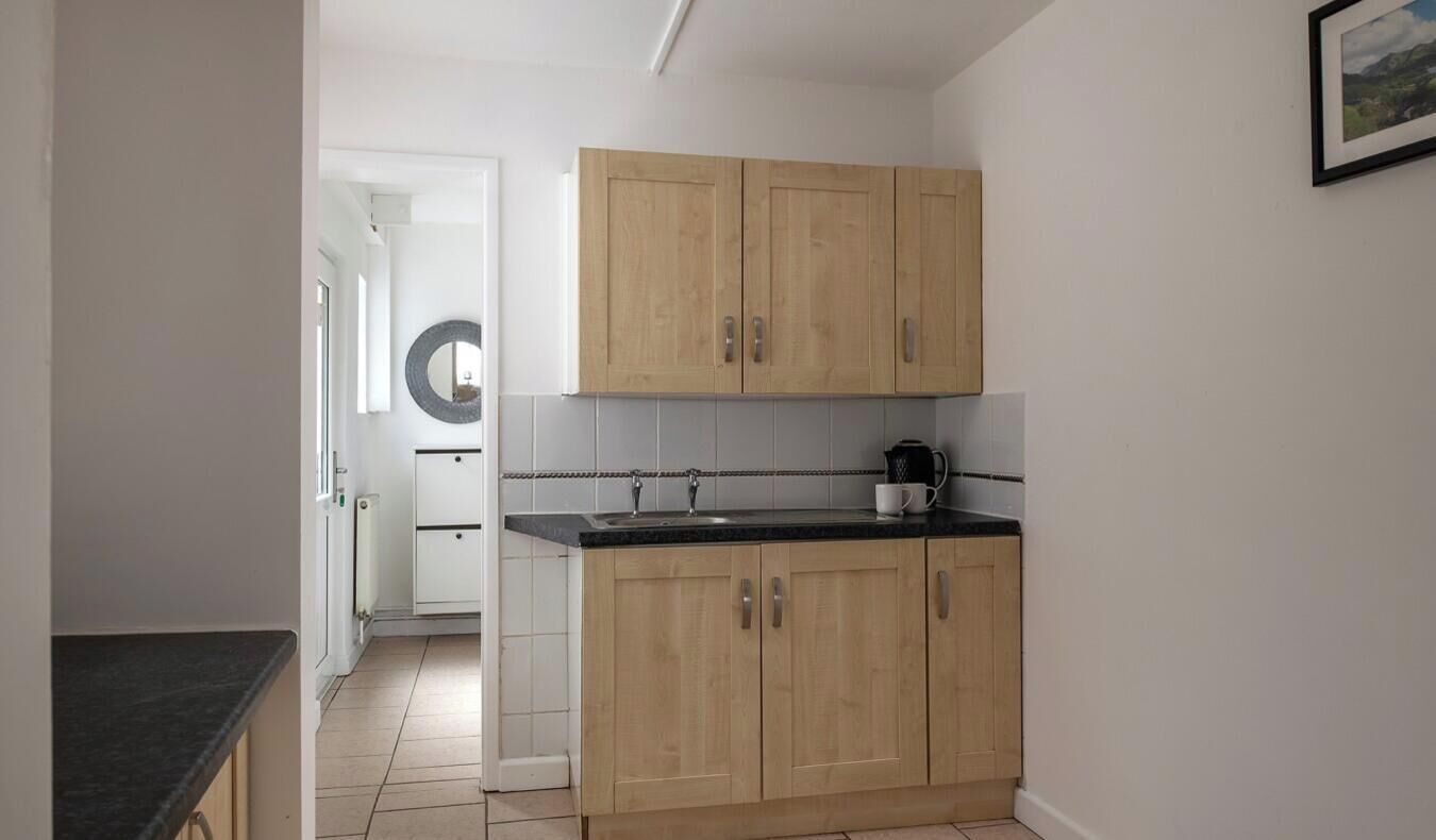 Una cucina con mobili in legno, un piano di lavoro nero e un rivestimento a parete bianco in piastrelle.