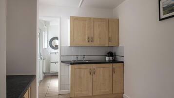 Una cucina con mobili in legno, un piano di lavoro nero e un rivestimento a parete bianco in piastrelle.
