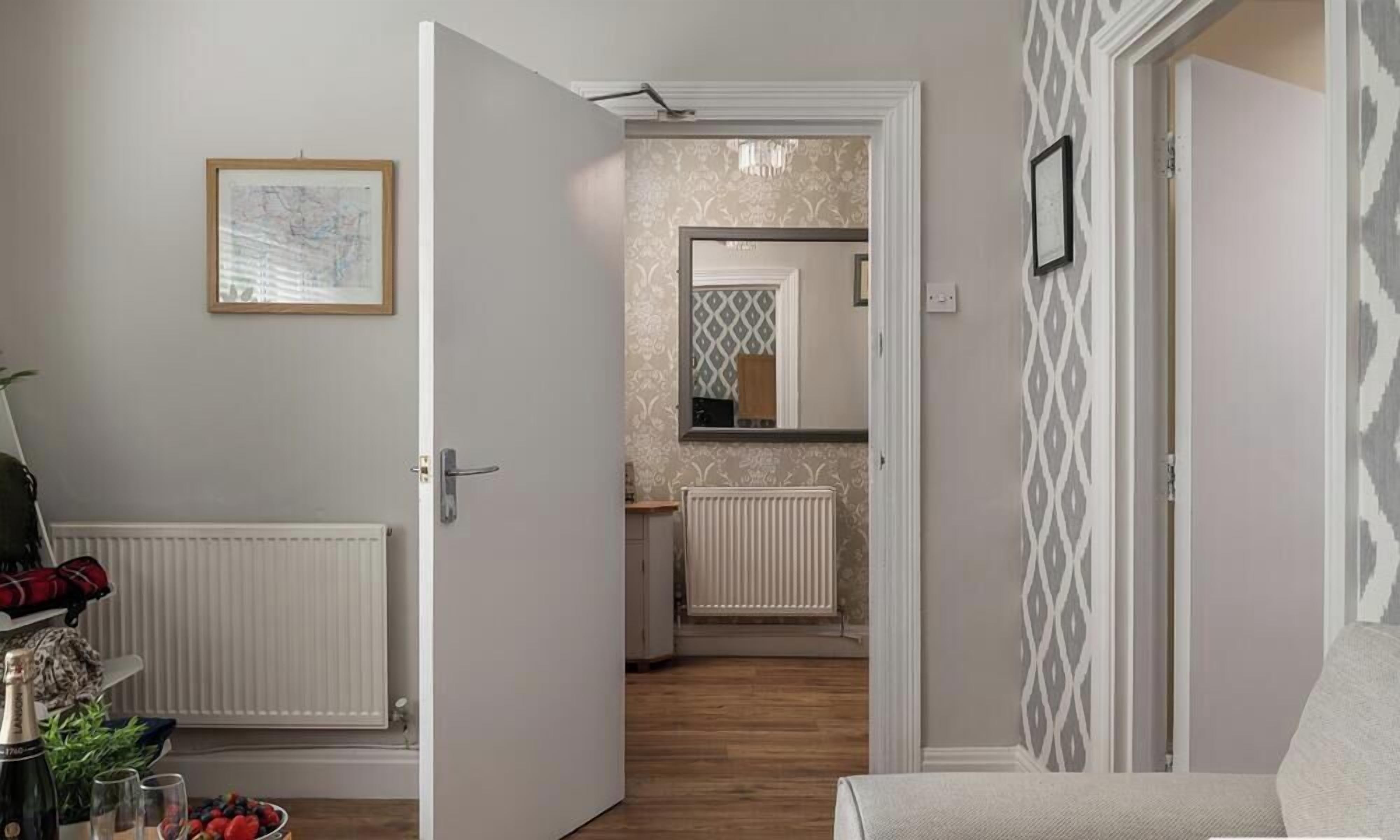 A hallway with a door leading to a bathroom, a radiator, and a framed picture on the wall.