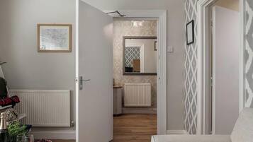 A hallway with a door leading to a bathroom, a radiator, and a framed picture on the wall.