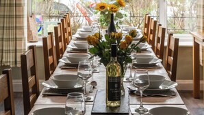 Une table à manger dressée pour un repas, avec une bouteille de vin, des assiettes et des verres.
