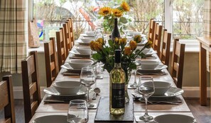 A dining table set for a meal with a bottle of wine, plates, and glasses. - Glyn Afon: At the foot of Mount Snowdon! (Llanberis)