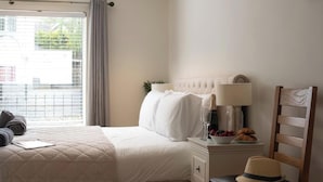 Une chambre à coucher avec un lit, une table de chevet avec une lampe, un bol de fruits et un chapeau.