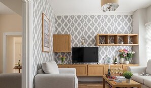 A living room with a TV, wooden shelves, a sofa, and a coffee table.