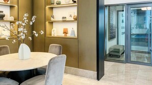 Un interior moderno con una mesa redonda, sillas, un florero con flores y estanterías con varios objetos decorativos.