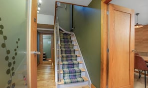 A staircase with a plaid carpet, a wooden door, and a glass wall with a decorative pattern.