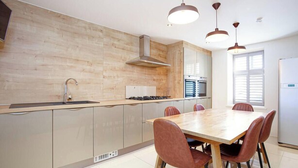 Una cocina moderna con una isla central, electrodomésticos de acero inoxidable e iluminación colgante.