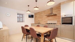Una cocina moderna con una mesa y sillas de madera, estufa, horno y un reloj en la pared.